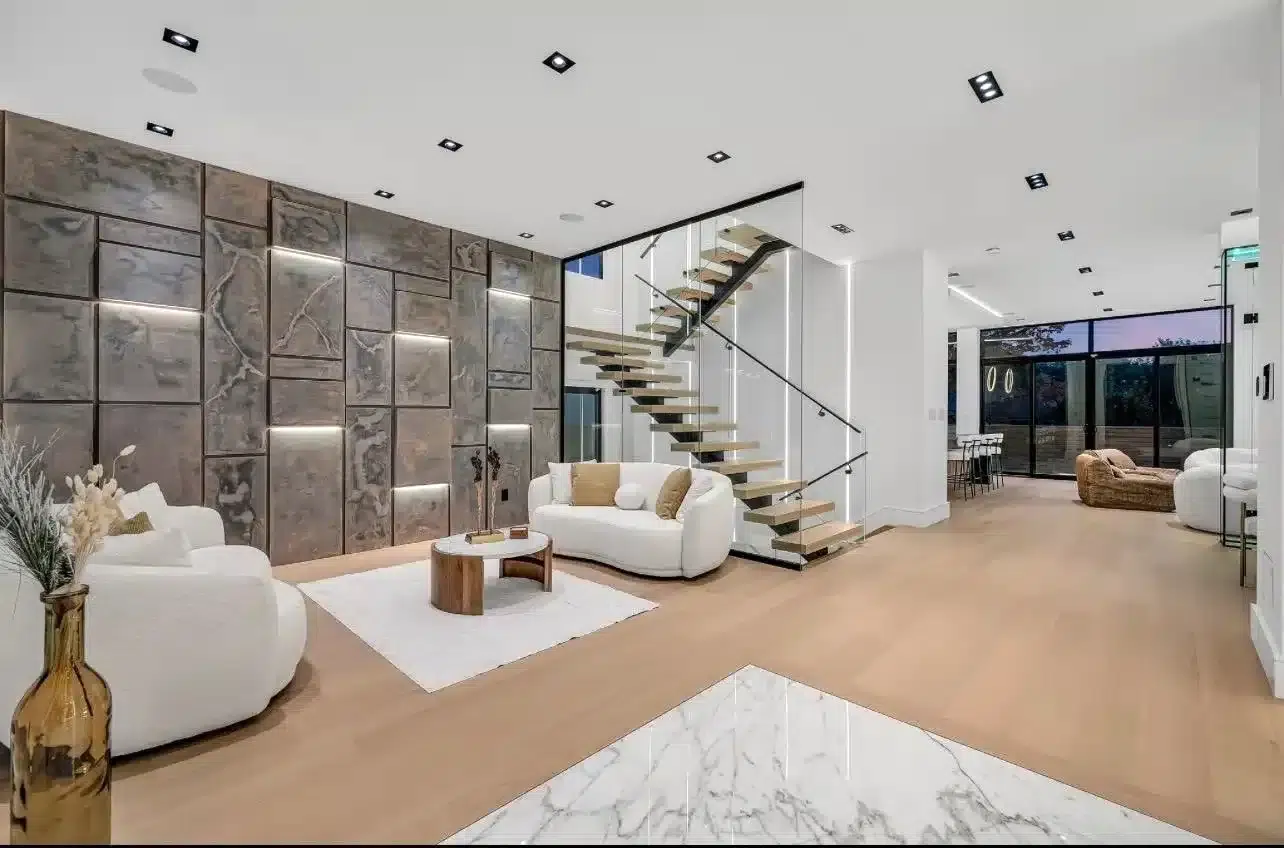 Floor to Ceiling Glass Railing Floor to ceiling glass panels enclosing a floating oak staircase with a black handrail in a modern open concept living room