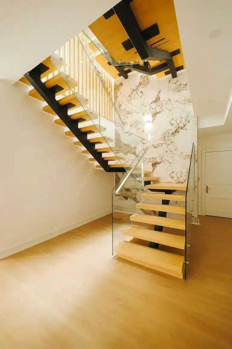 Frameless Glass Railing with Stainless Handrail Frameless glass railing with a stainless steel handrail on a floating mono stringer staircase in front of a marble wall