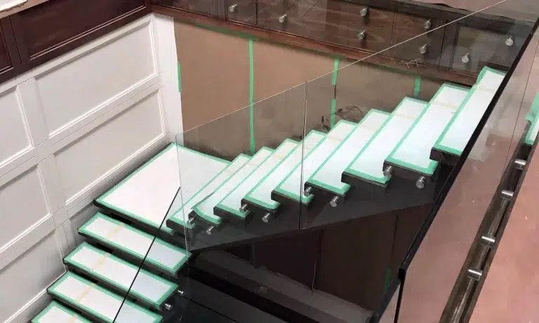 Frameless glass railing fixed with stainless steel standoffs along a staircase and upper landing during installation