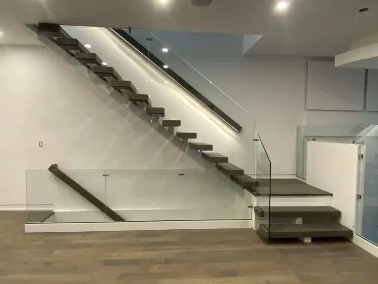Topless glass railing with no top rail along a floating staircase with dark wood treads and a matching glass panel around the lower stair opening